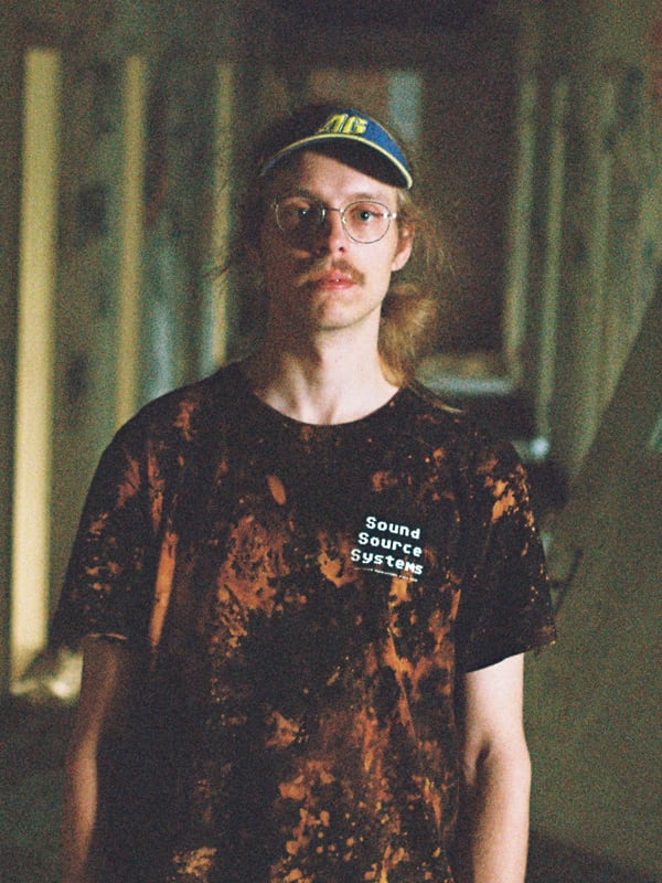 Tomas in a Sound Source Systems shirt and cap, standing in an abandoned building
